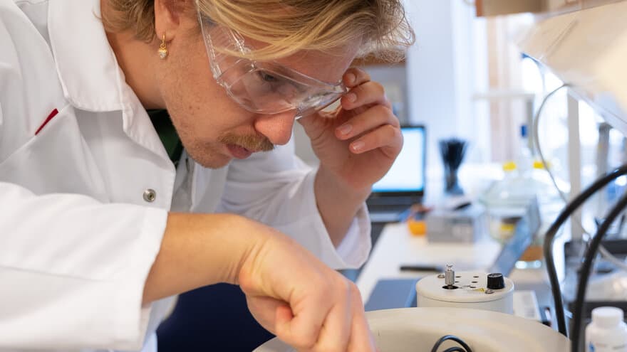 Mannlig fysikkstudent med vernebriller tester instrumenter på lab