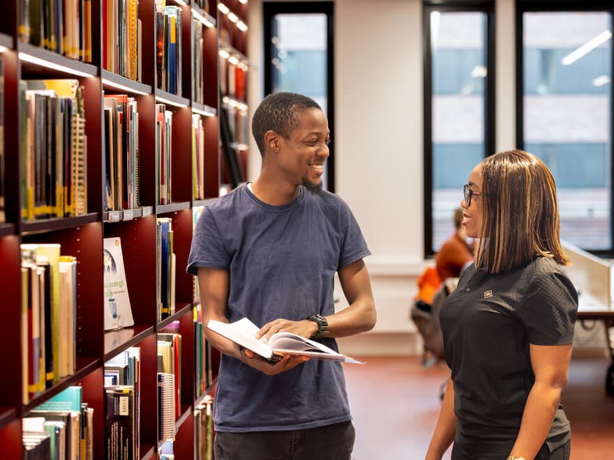 Studenter i Universitetsbiblioteket ser på bøker.