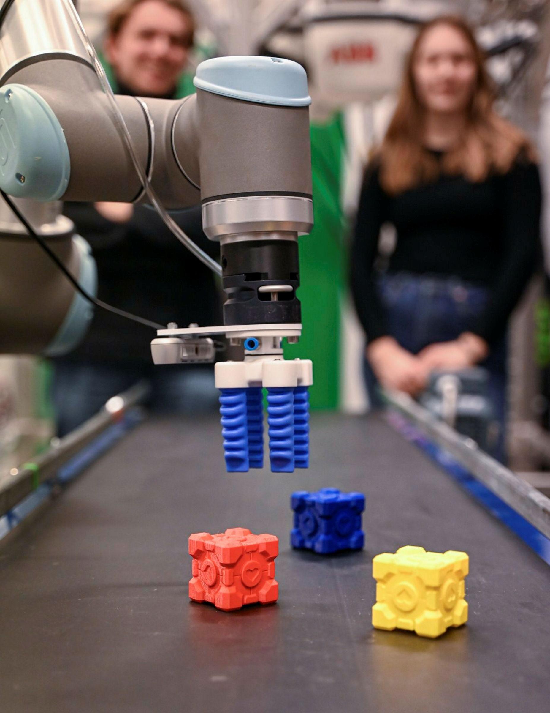 Studenter jobber med programmering av robotarm på lab