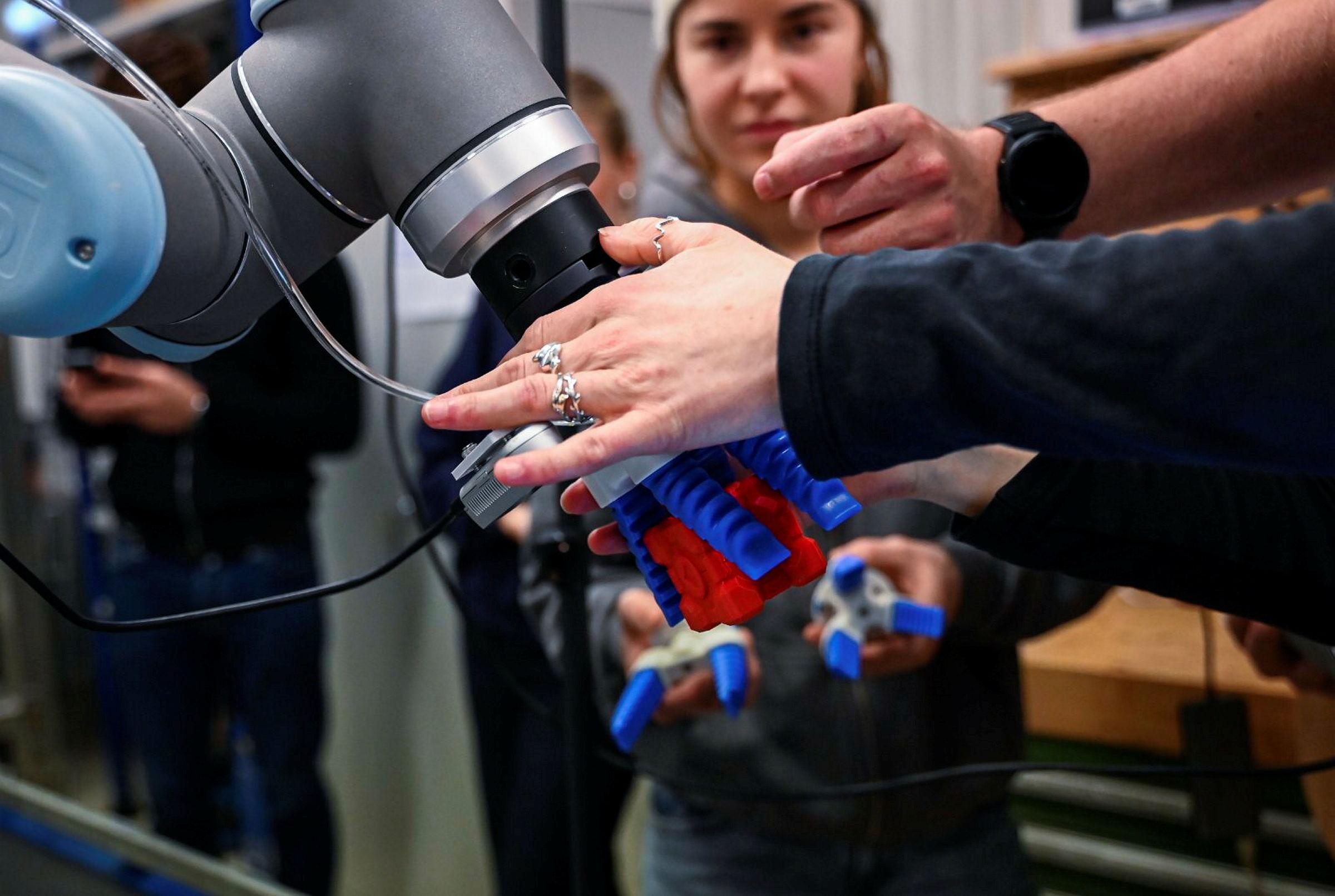 Studenter jobber med programmering av robotarm på lab