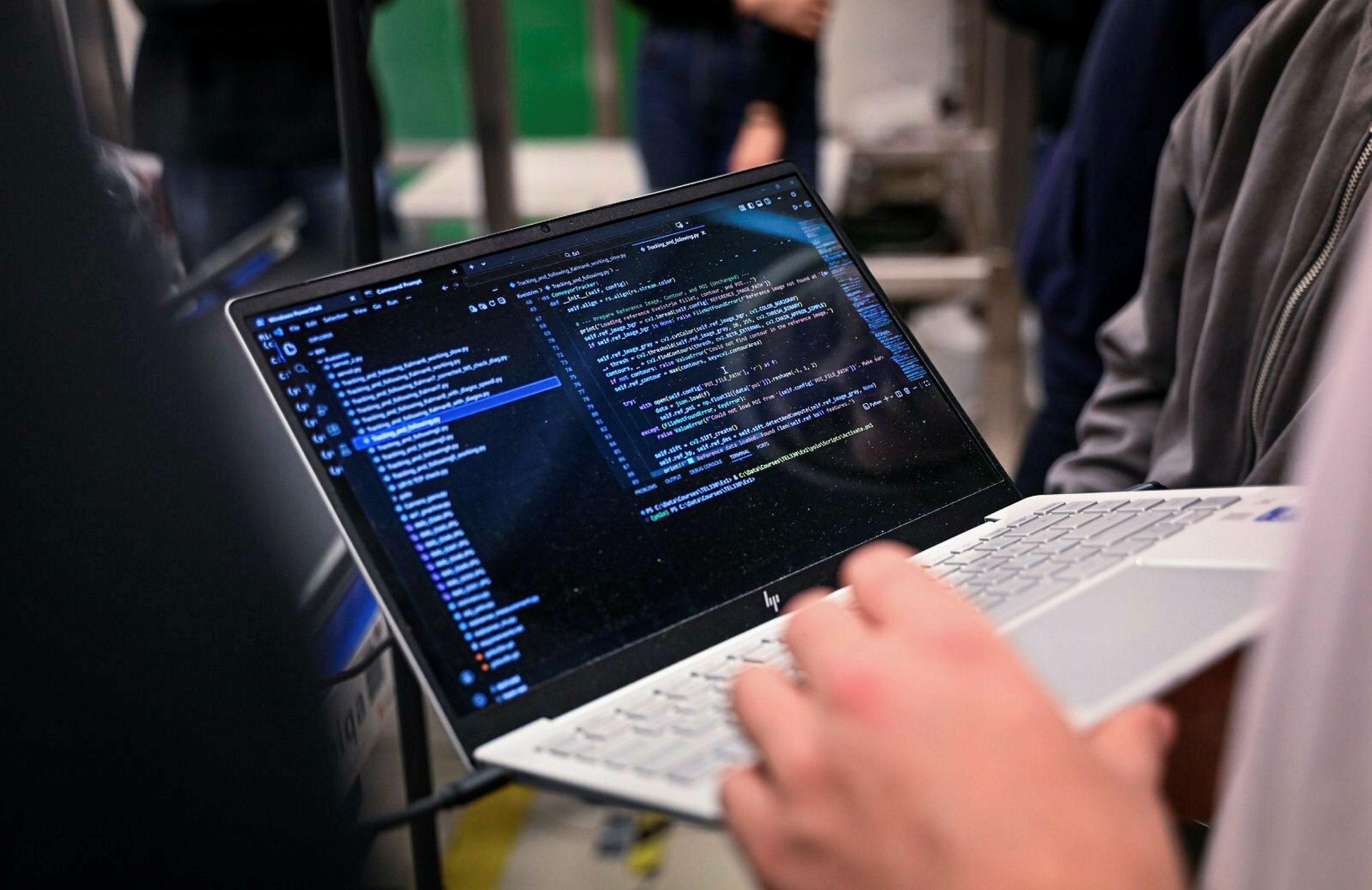 Studenter jobber med programmering av robotarm på lab