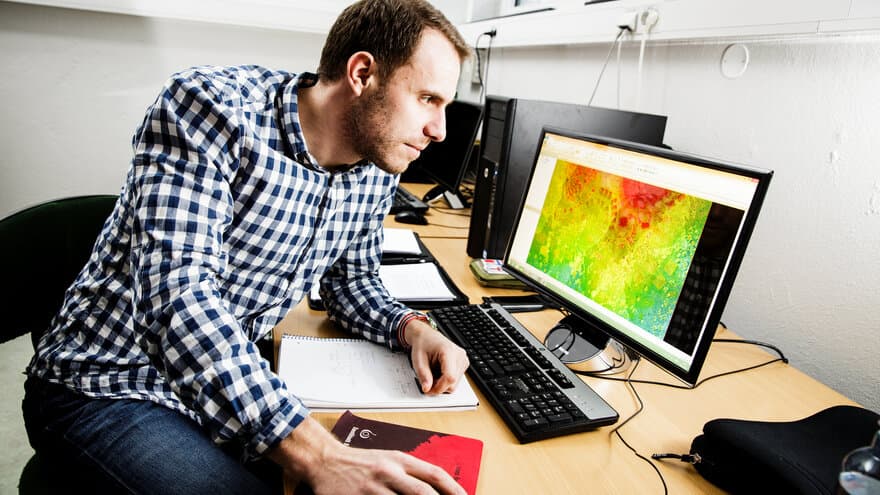 Magnus Oshaug, masterstudent i geomatikk. Bildet på  dataskjermen er en punktsky fra flybåren laserskanning av et landskap.