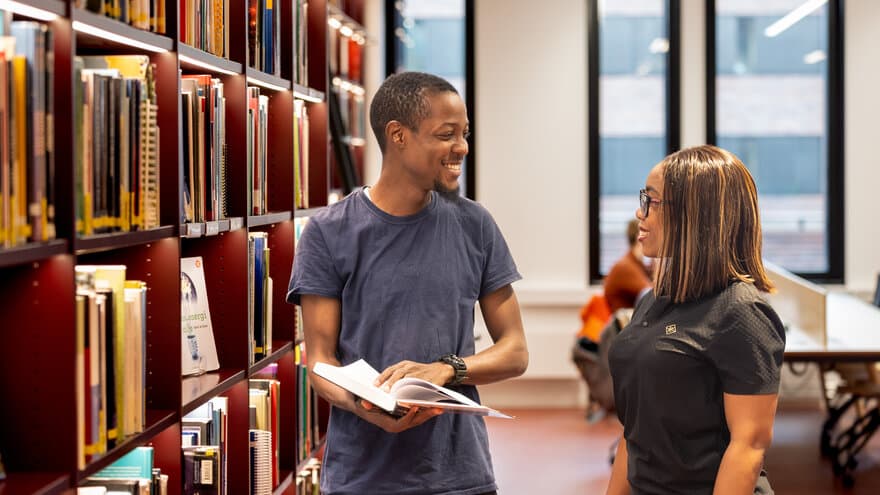 Studenter i Universitetsbiblioteket ser på bøker.