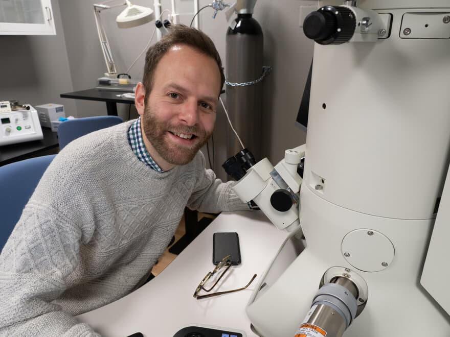 Fredrik Strebel Skedsmo sitter ved et elektronmikroskop